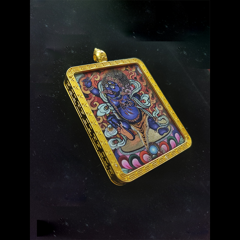 Angled high-angle shot of an Acala (Fudo Myoo) protection pendant, the zodiac guardian for the Year of the Rooster, featuring the wrathful deity in a gold-tone frame.