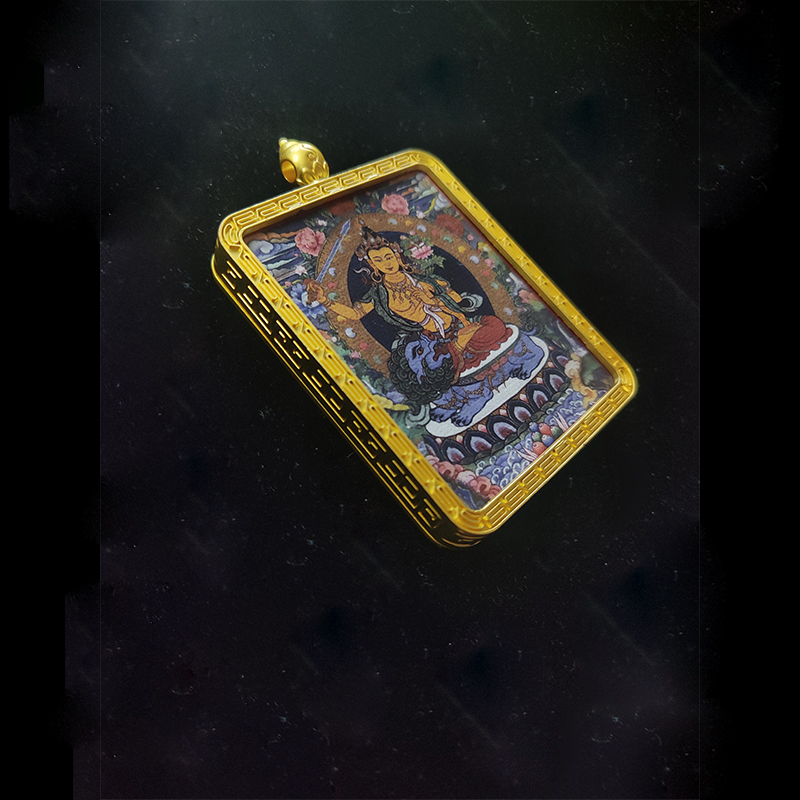 Angled high-angle view of a Manjushri Bodhisattva pendant in a gold-tone frame, featuring the Buddha of Wisdom on a blue lion, the dedicated guardian for the Year of the Rabbit.