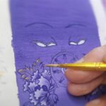 Hand-painting process of a purple Buddha Eyes Thangka with gold ink detailing and sacred geometry.