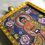 Close-up of Amitabha Buddha pendant in gold Gau box for zodiac guardian meditation.