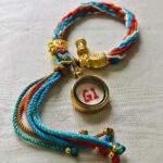 Backside view of the red Amitayus charm bracelet showing the authentic brand emblem.