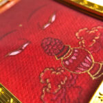 Macro detail of hand-painted gold linework on Amitayus Buddha Eyes red fine art canvas.