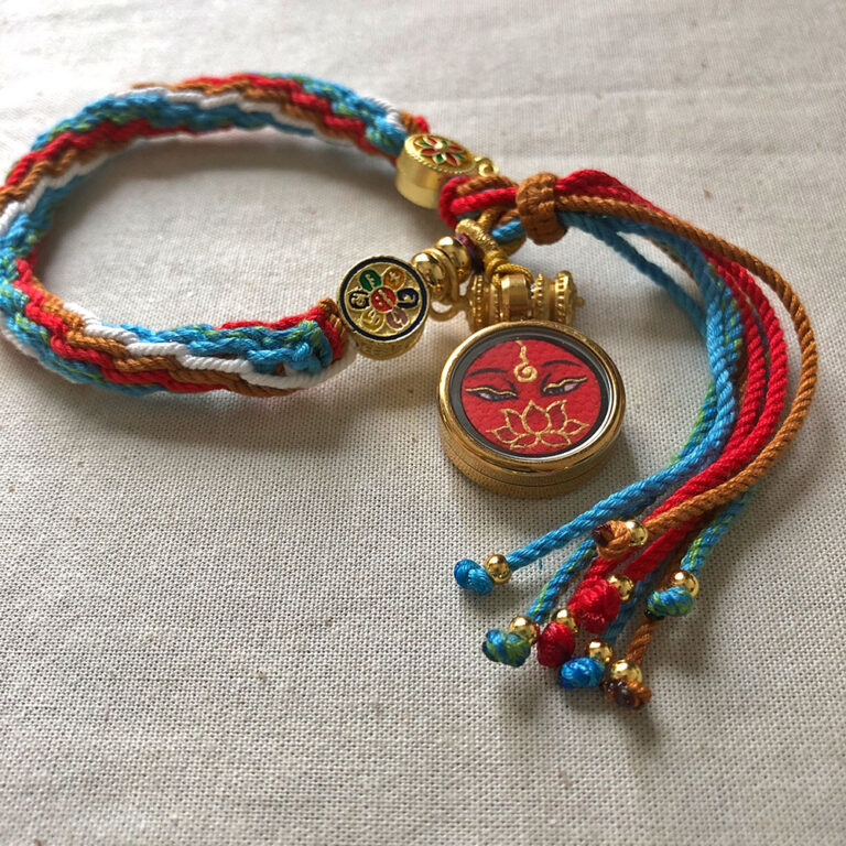 Flatlay layout of the red Amitayus Buddha Eyes braided cord bracelet.