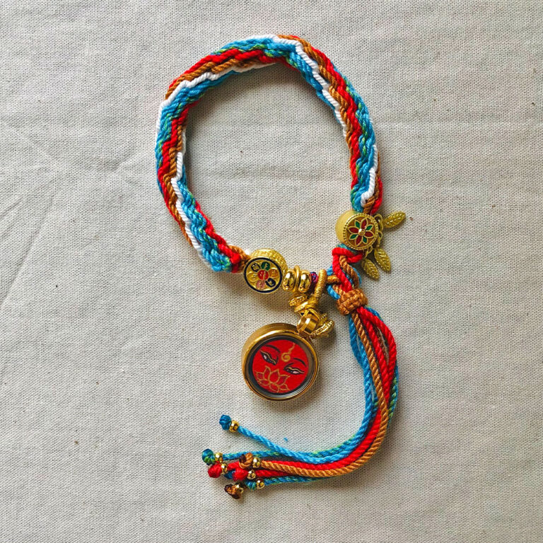 Full view of red Amitayus Buddha Eyes pendant and braided cord.