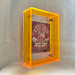 Side perspective of red Amitayus Thangka print inside a yellow translucent acrylic frame.