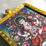 Close-up of Four-Armed Avalokiteshvara pendant in gold Gau box for zodiac guardian meditation.