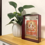 Orange Four-Armed Avalokiteshvara Thangka red acrylic art block next to indoor plant.