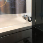 Close-up of magnetic corner screw on smoky black translucent acrylic display block.