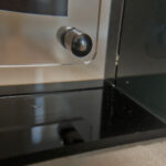 Close-up of magnetic corner screw on smoky black translucent acrylic display block.