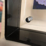 Close-up of magnetic corner screw on dark translucent black acrylic display block.