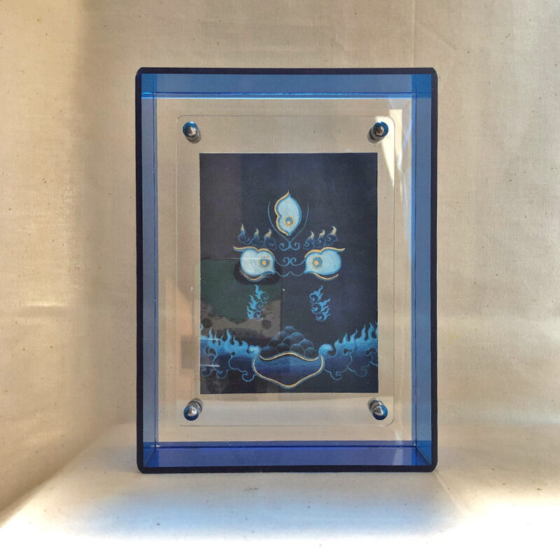 Front view of Black Jambhala Buddha Eyes print in a blue floating translucent acrylic frame.