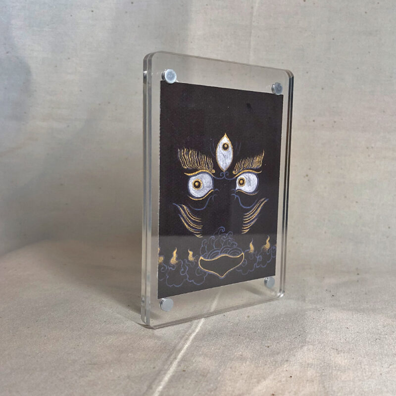 Side-angle view of freestanding clear acrylic block displaying Black Jambhala line art.