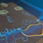 Close-up of original hand-painted gold linework and flame details on deep blue canvas texture.