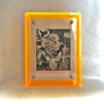 Front view of Black Jambhala Thangka print in a yellow floating translucent acrylic frame.