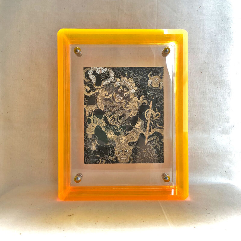 Front view of Black Jambhala Thangka print in a yellow floating translucent acrylic frame.