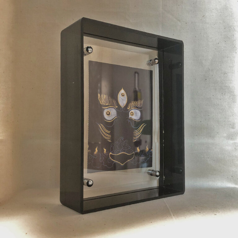 Side perspective of Black Jambhala Buddha Eyes art inside a black translucent acrylic frame.
