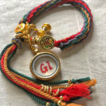 Backside of the Ghau box pendant handwritten with GI studio initials alongside gold Tibetan charm.