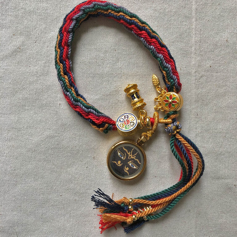 Black Padmasambhava Buddha Eyes Tibetan braided meditation bracelet flatlay on fabric.