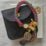 Black Padmasambhava Buddha Eyes braided cord bracelet shown with signature black pouch and gift box.