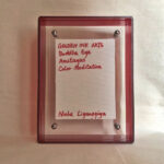 Back view of red acrylic frame displaying Golden Ink Arts custom branding card and signature.