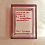 Back view of red acrylic frame displaying Golden Ink Arts custom branding card and artist signature.