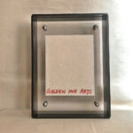 Back view of black acrylic frame displaying Golden Ink Arts custom branding card.