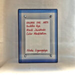 Back view of blue acrylic frame displaying Golden Ink Arts custom branding card and signature.