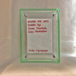 Back view of green acrylic frame displaying Golden Ink Arts custom branding card and signature.