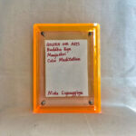 Back view of yellow acrylic frame displaying Golden Ink Arts custom branding card and artist signature.