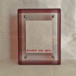 Back view of red acrylic frame displaying Golden Ink Arts custom branding card.