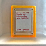 Back view of yellow acrylic frame displaying Golden Ink Arts custom branding card and artist signature.