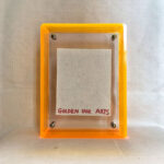 Back view of yellow acrylic frame displaying Golden Ink Arts custom branding card.