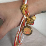 Person wearing the Golden Shakyamuni Buddha Eyes braided cord bracelet on wrist.