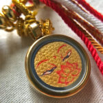 Close-up view of Golden Shakyamuni Buddha Eyes artwork with hand-applied gold linework in a Ghau box pendant.