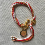 Golden Shakyamuni Buddha Eyes Tibetan braided meditation bracelet flatlay on fabric.