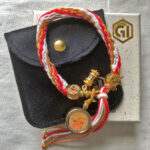 Golden Shakyamuni Buddha Eyes braided cord bracelet shown with signature black pouch and gift box.