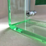 Close-up of magnetic corner screw on emerald green translucent acrylic display block.