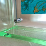 Close-up of magnetic corner screw on emerald green translucent acrylic display block.