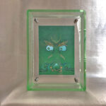 Front view of Green Jambhala Buddha Eyes print in a green floating translucent acrylic frame.