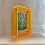 Side perspective of Green Jambhala Thangka print inside a yellow translucent acrylic display frame.