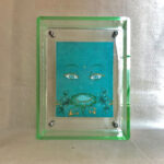 Front view of Green Tara Buddha Eyes print in a green floating translucent acrylic frame.