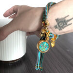 Green Tara Buddha Eyes charm bracelet worn on wrist for spiritual protection.