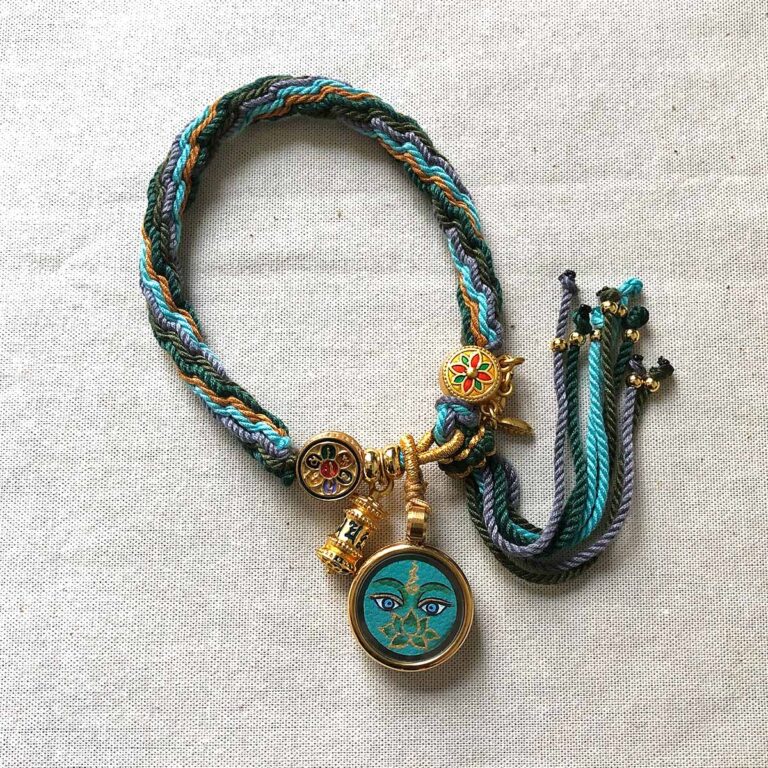 Full view of Green Tara Buddha Eyes pendant and braided cord.