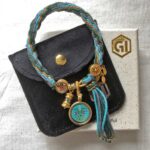 Green Tara Buddha Eyes bracelet displayed with black velvet pouch and Golden Ink Arts box.