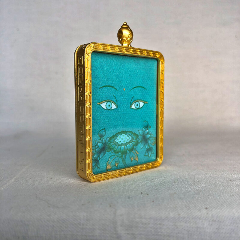 Three-quarter side angle of Green Tara Buddha Eyes gold brass Gau box pendant.