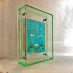 Side perspective of Green Tara Buddha Eyes art inside a green translucent acrylic frame.