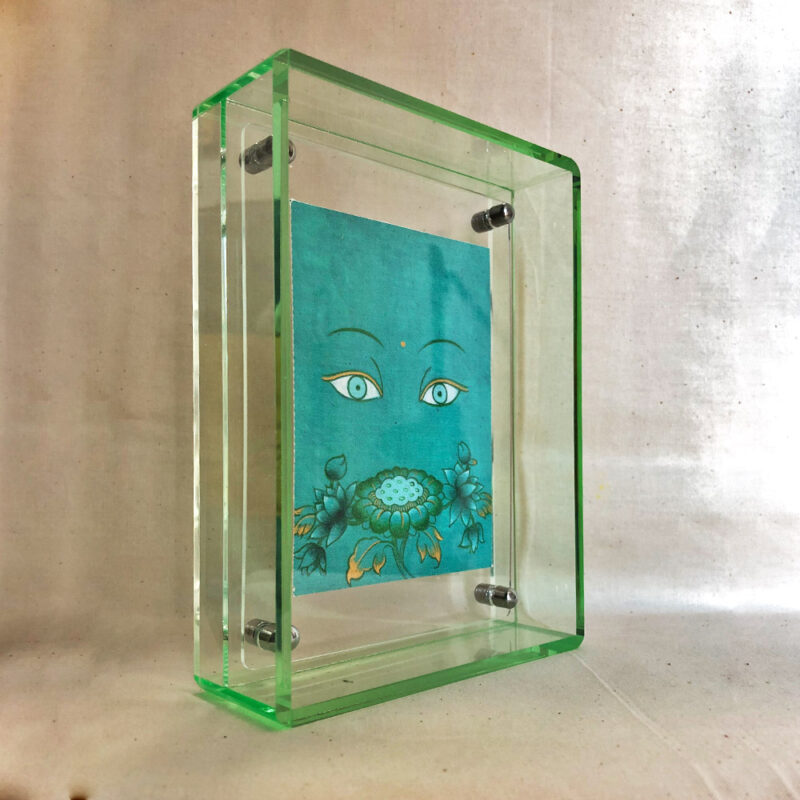 Side perspective of Green Tara Buddha Eyes art inside a green translucent acrylic frame.