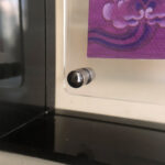 Close-up of magnetic corner screw on smoky grey translucent acrylic display block.