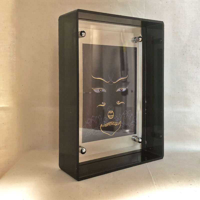 Side perspective of Padmasambhava Buddha Eyes art inside a black translucent acrylic frame.