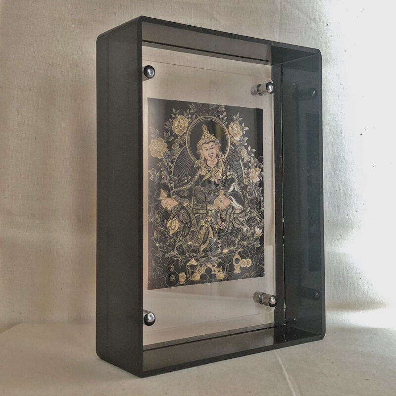 Side perspective of Guru Rinpoche Thangka print inside a dark translucent black acrylic frame.